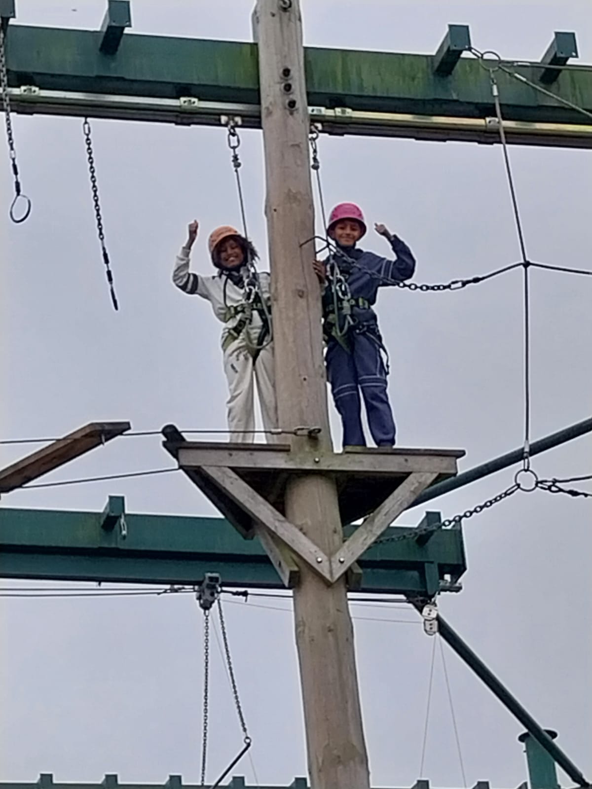 Two boys with smiles and thumbs up on the high rope course