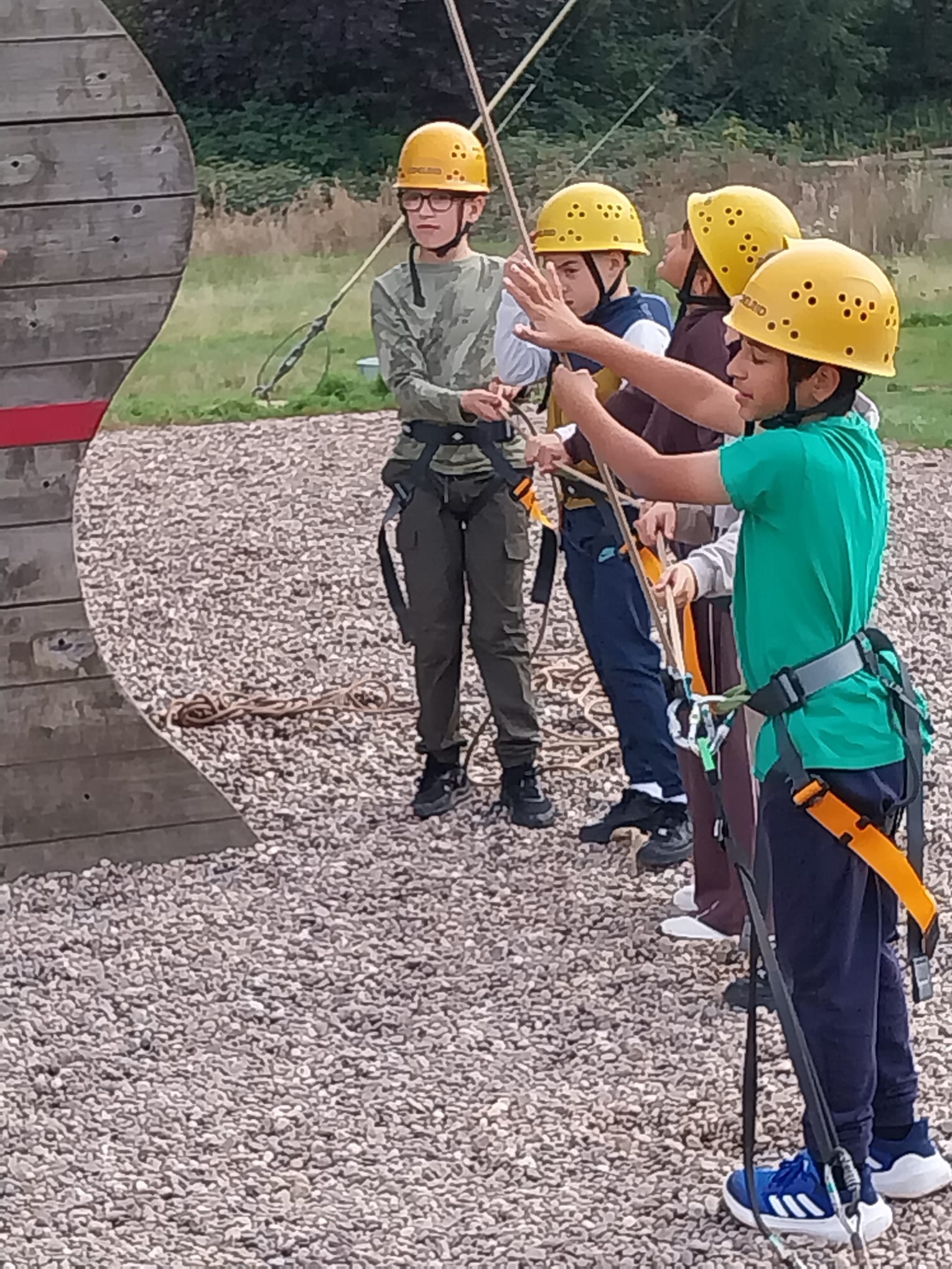 Group of children helping pull up classmate who is climbing the wall