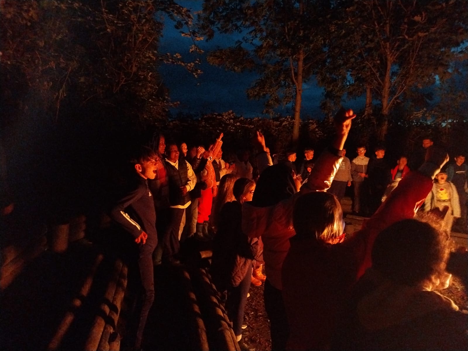 Group of children singing around a campfire