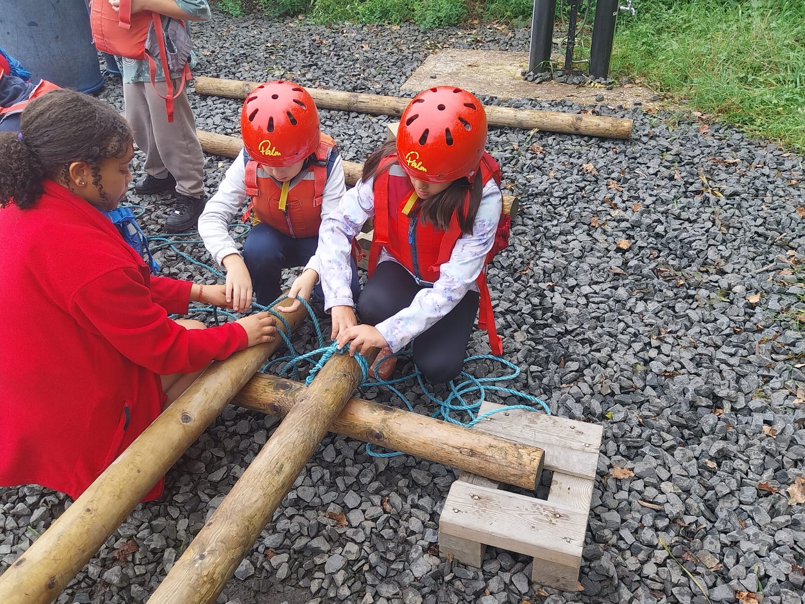 Some children tying knots to build a raft