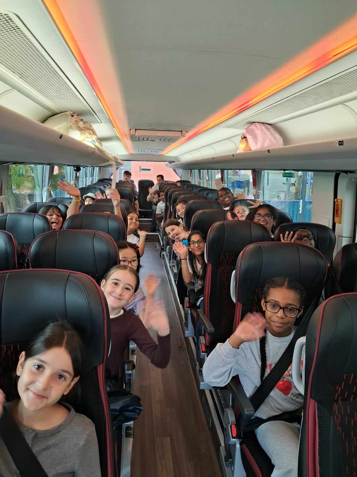 Year 5 & 6 children on a coach waving